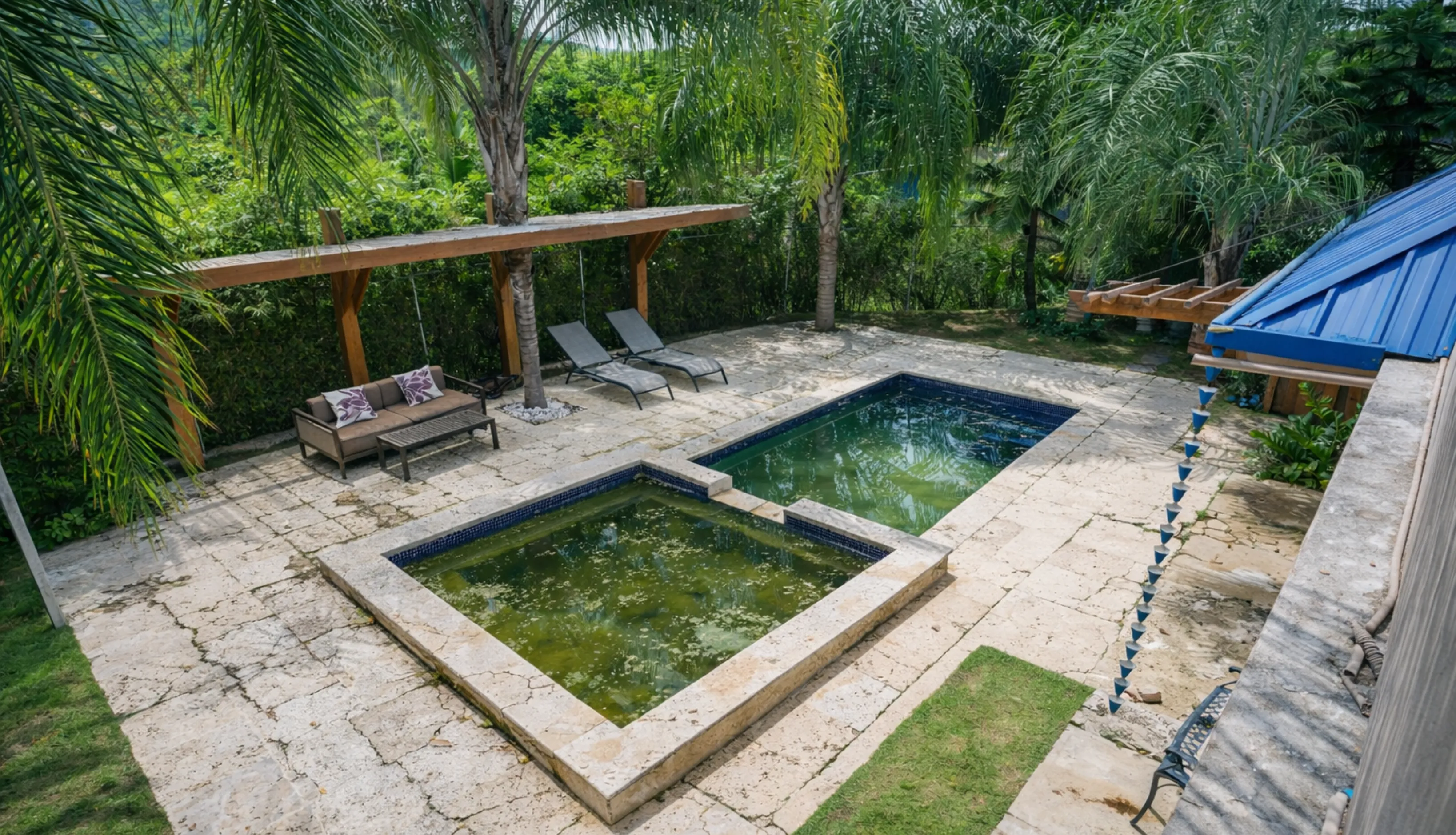 An outdated and neglected rectangular pool in Los Angeles with stained plaster and cracked stone decking before a professional remodeling project
