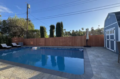 New custom pool with premium blue tile finish being filled for the first time after successful construction.